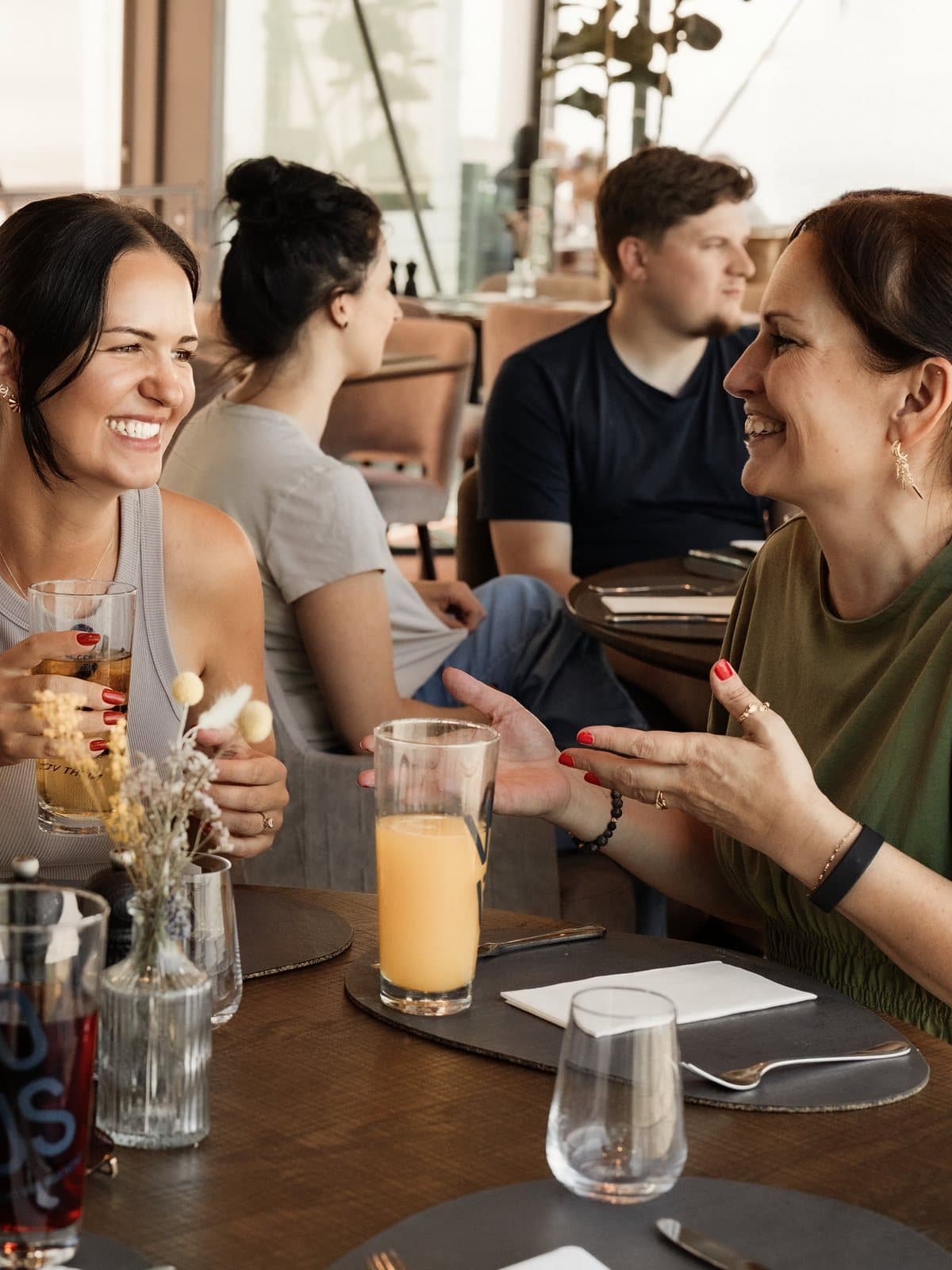 Kolleginnen lachen beim gemeinsamen Mittagessen im Lokal